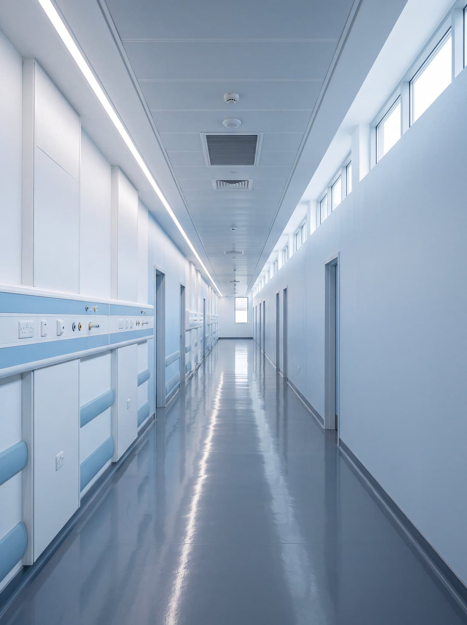 Empty modern hospital corridor with bedhead services along the wall